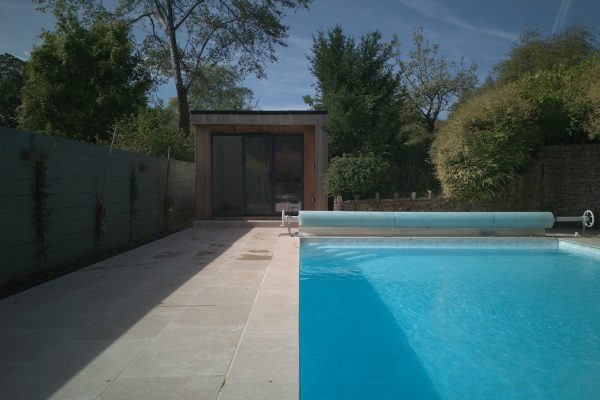 Bespoke cedar-clad pool house with glazed bi-fold doors overlooking the outdoor swimming pool.